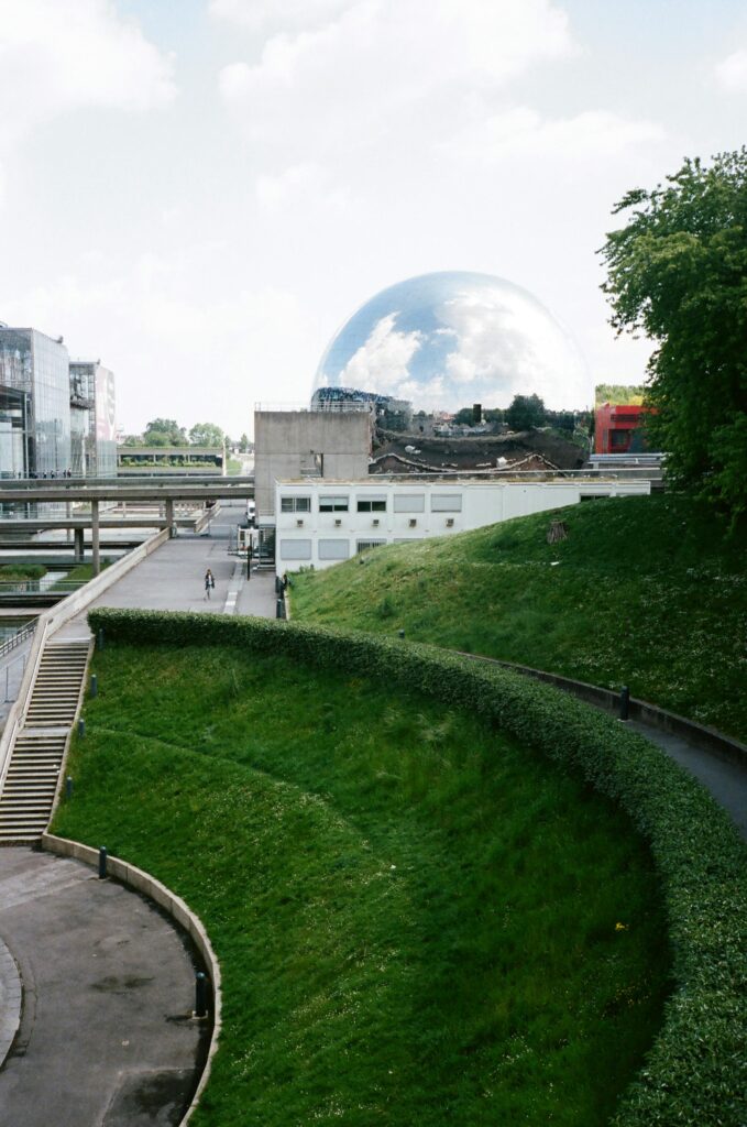 Green park landscape with a unique architectural dome and surrounding buildings.