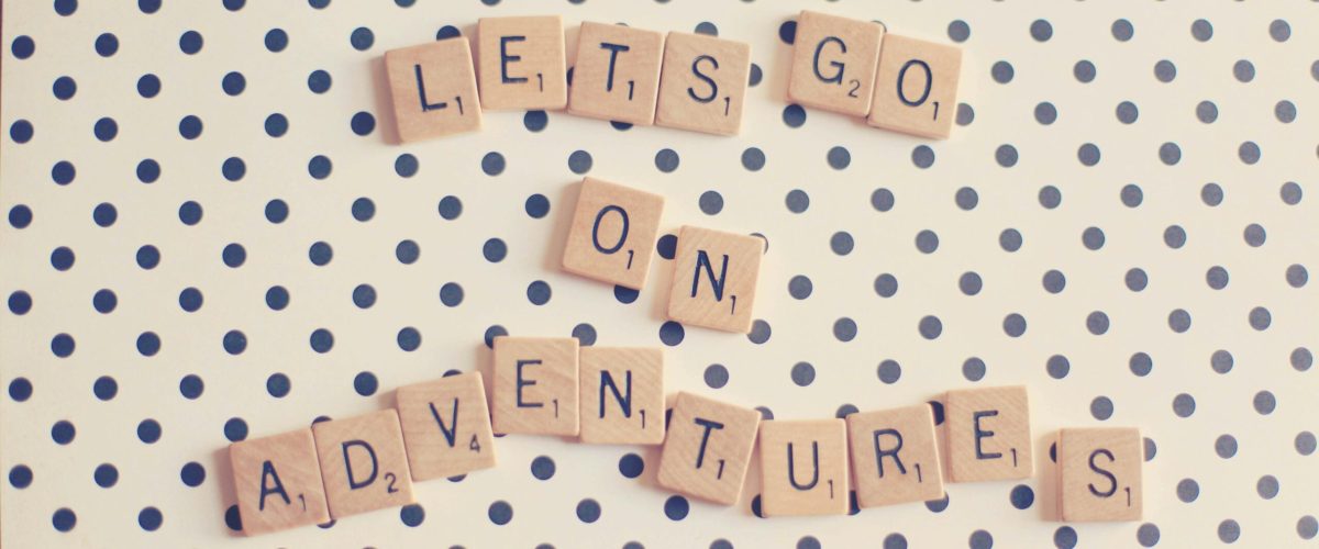 Scrabble tiles spell 'Let's go on adventures' on a polka dot background.